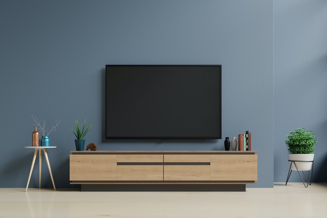 TV mounted above a cabinet on a blue wall.